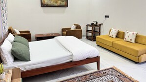 Ein Hotelzimmer mit einem Bett, zwei Sesseln, einer Couch, einem kleinen Tisch und einem Bild an der Wand.