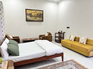 A hotel room with a bed, two armchairs, a sofa, a small table, and a painting on the wall. - Cozy 1-bedroom on a rooftop in a bungalow Jaipur with terrace garden (Jaipur)