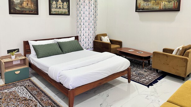 Ein Hotelzimmer mit einem Bett, zwei Sesseln, einem kleinen Tisch und zwei Bildern an den Wänden.