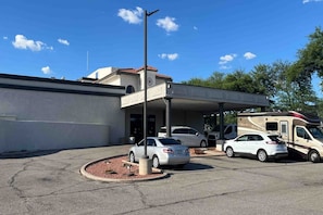 A parking area with a covered structure, two cars, and a camper. - 1 King Bed | Suite, Non-Smoking, Micfridge (Tucson AZ)