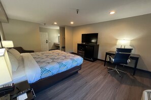Ein Hotelzimmer mit Bett, Schreibtisch mit Stuhl, Fernseher und Bad.