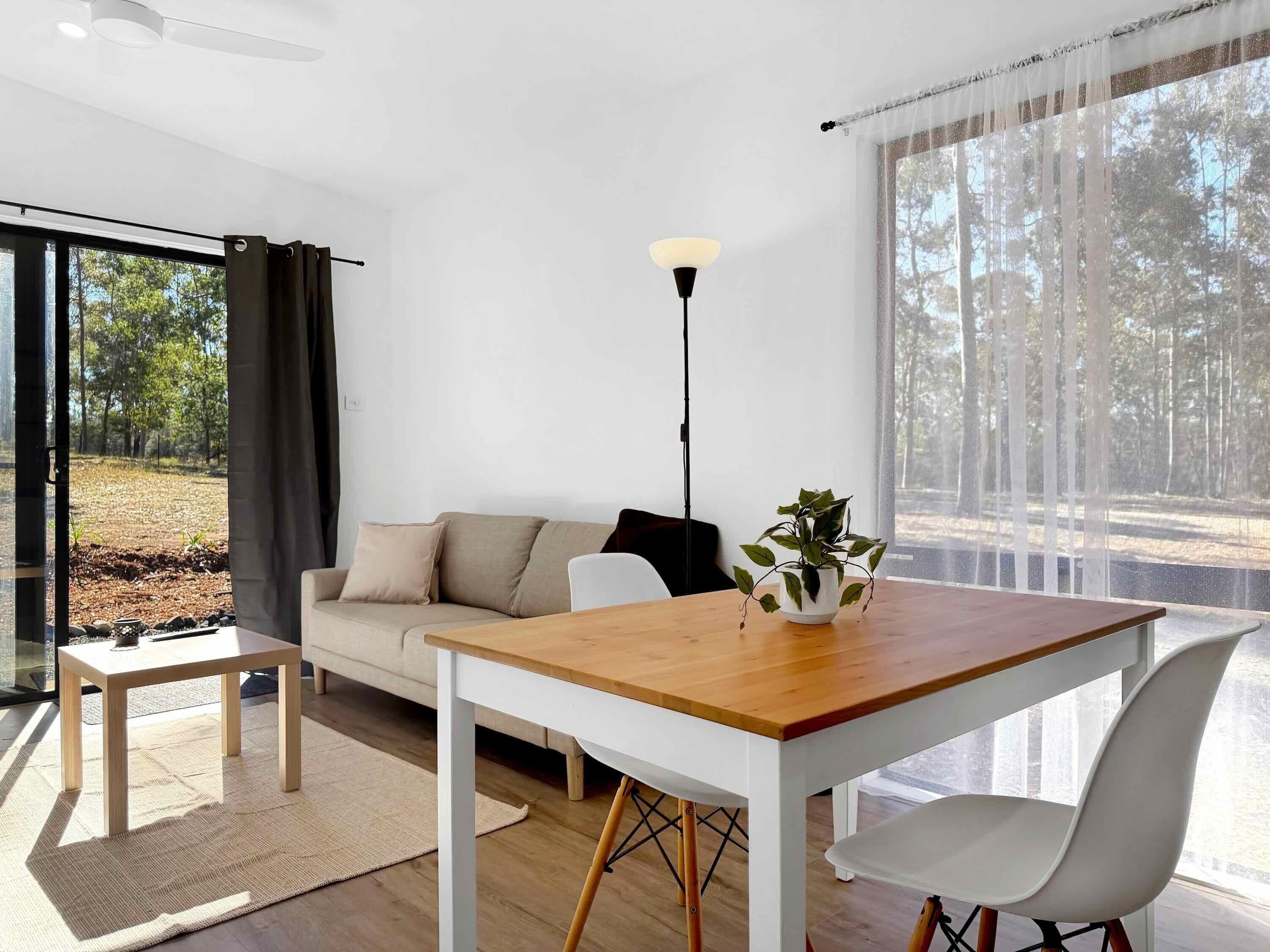 Un salon moderne avec une table en bois, un canapé blanc et une plante en pot.