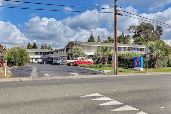 A motel with a parking lot, a red car parked in front, and a signboard. - 1 Queen Bed|Non-Smoking,Mini Fridge (Santa Rosa CA)