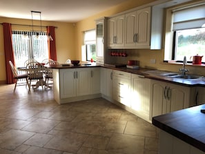 A kitchen with white cabinets, a dining table with chairs, and a window with curtains.