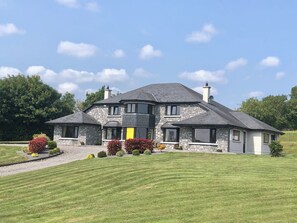 A two-story house with a stone facade, multiple windows, and a well-maintained lawn. - Family run boutique self-catering house, with homemade baking on arrival. (Doneraile, Co Cork)