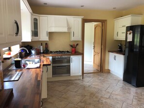 A kitchen with white cabinets, a wooden countertop, a gas stove, an oven, and a black refrigerator. - Family run boutique self-catering house, with homemade baking on arrival. (Doneraile, Co Cork)