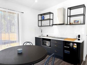 Une cuisine compacte avec une table ronde, des appareils électroménagers intégrés et une vue par la fenêtre.