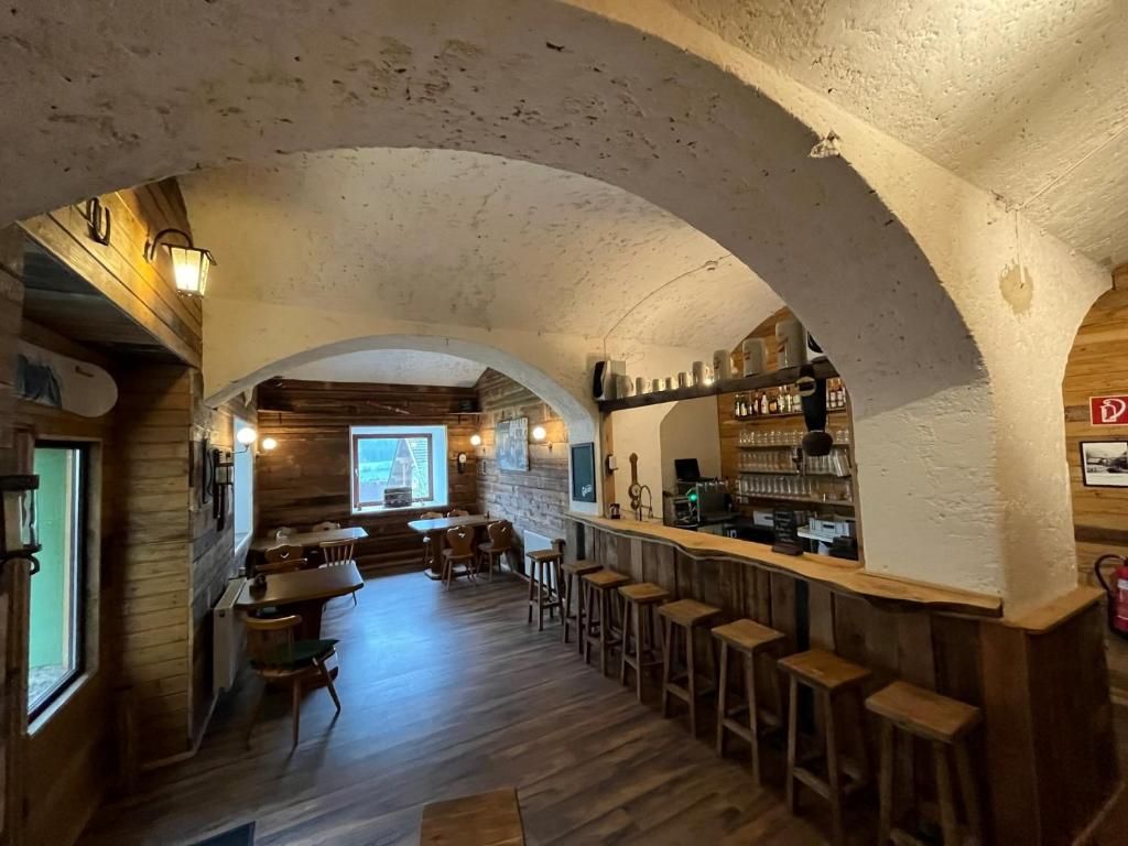 A rustic interior with a bar area, wooden furniture, and a vaulted ceiling.