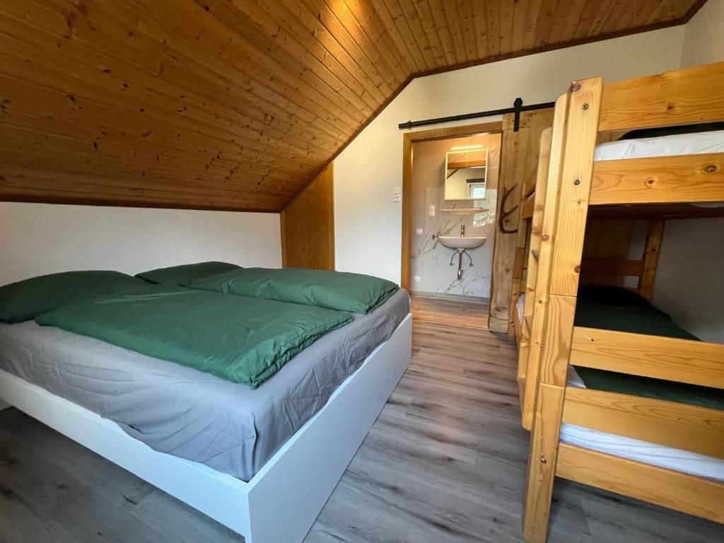 Et værelse med køjeseng, enkeltseng og badeværelse med vask og spejl.