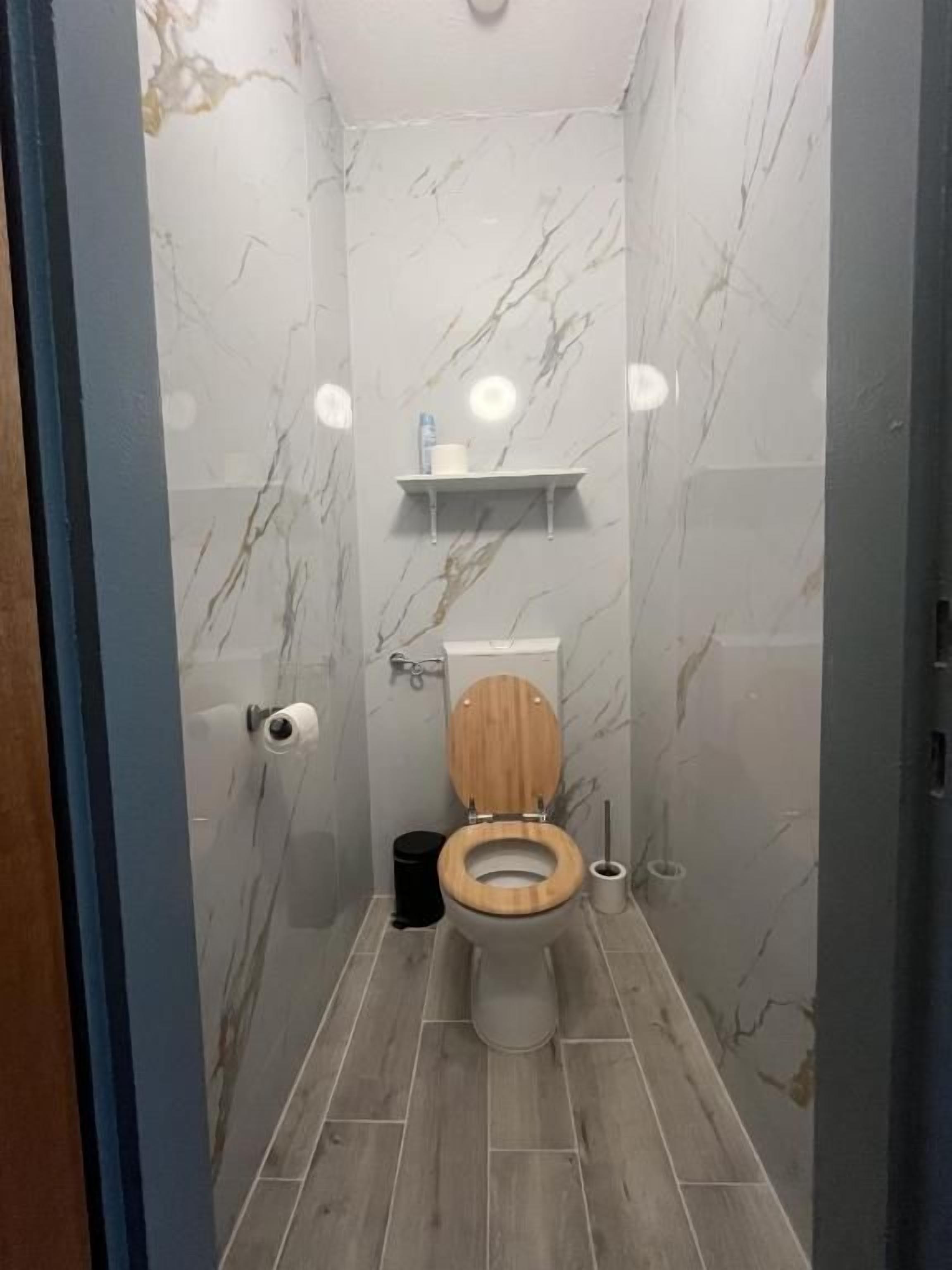Une salle de bain avec des toilettes, des murs en marbre et un plancher en bois.