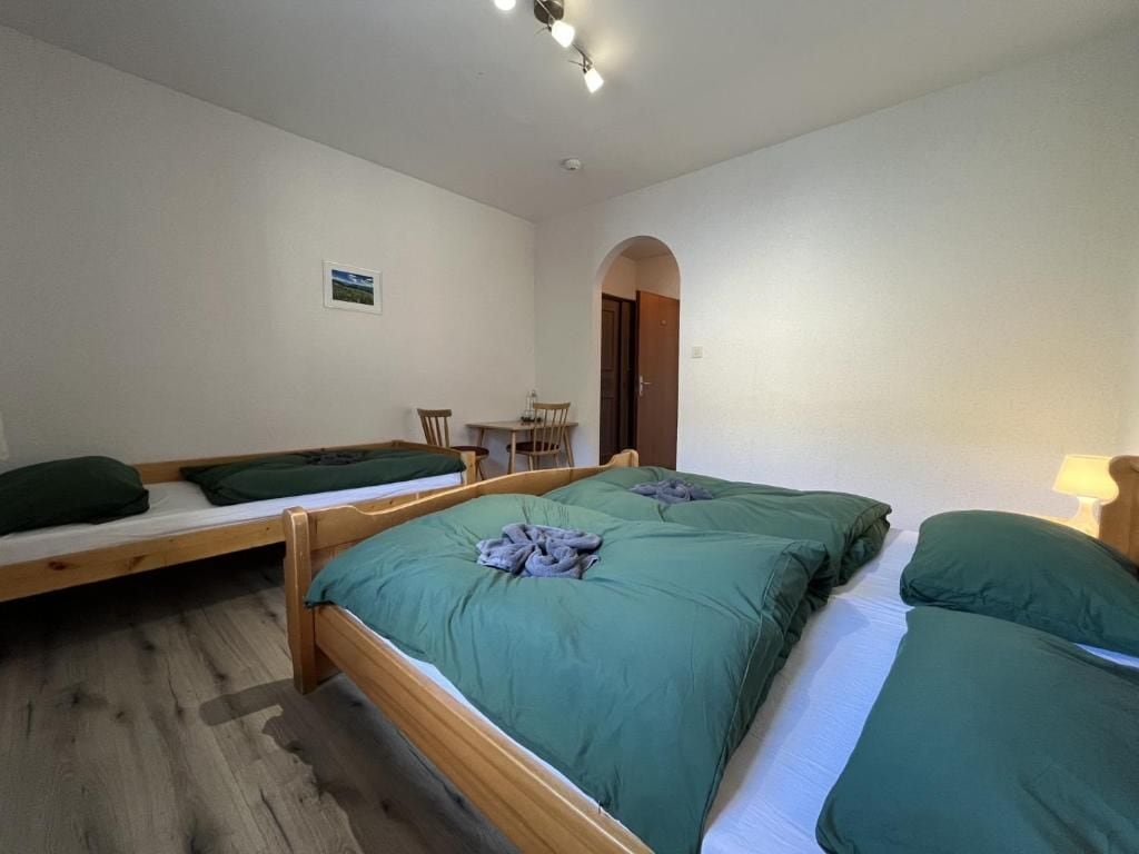A room with two wooden beds, a small table with chairs, and a door leading to another room.
