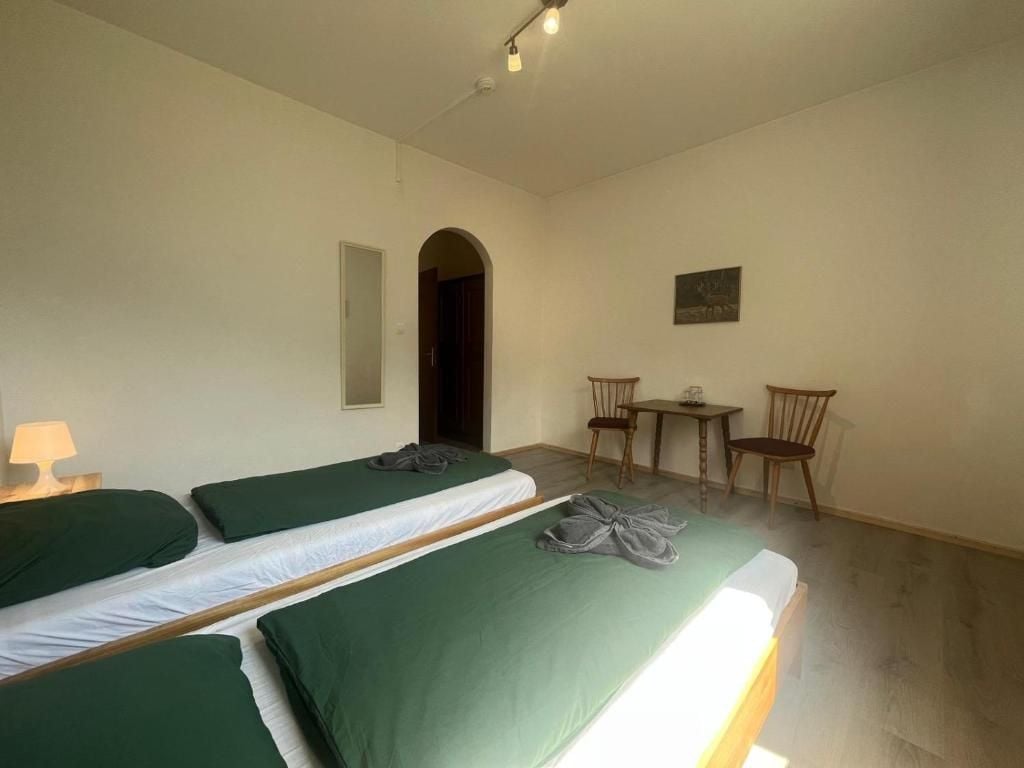 A room with two single beds, a small table, two chairs, and a door leading to another room.