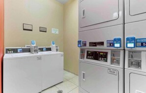A laundry facility with multiple washing machines and dryers, each with a control panel and a QR code for digital services.