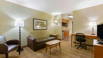 Une chambre d’hôtel équipée d’un canapé, d’une petite table, d’un bureau avec une chaise, d’une télévision et d’une kitchenette.