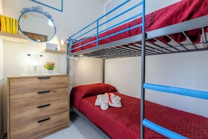 A bunk bed room with a wooden dresser, a mirror, and a small shelf with books. - 100 meters from the beach (Alghero)