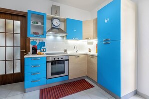 A modern kitchen with blue cabinets, a stainless steel oven, and a built-in microwave. - 100 meters from the beach (Alghero)