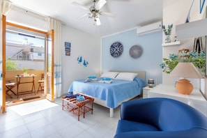 A bedroom with a bed, a desk, a chair, a ceiling fan, and a balcony. - 100 meters from the beach (Alghero)