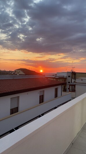 En takterrass med utsikt över solnedgången över ett bostadsområde.