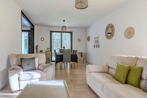 A modern living room with a sofa, a coffee table, and a dining area with chairs and a table.