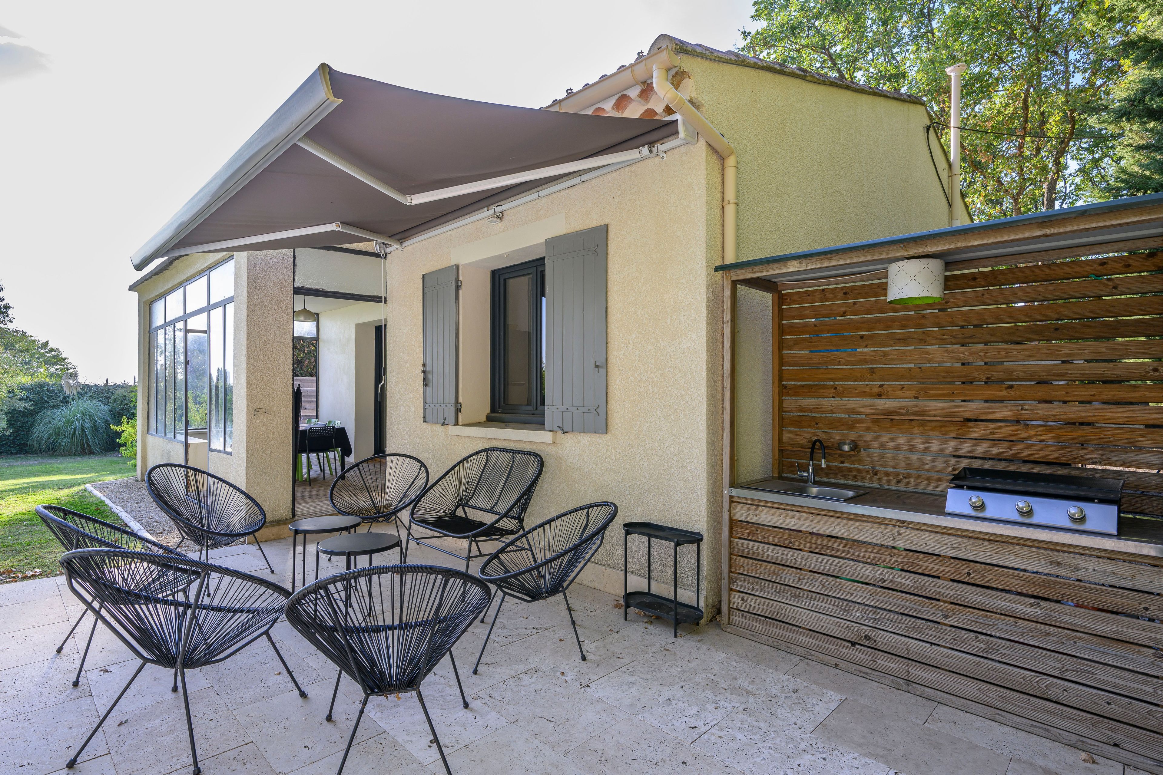 Une terrasse extérieure avec un ensemble de mobilier de jardin et un espace barbecue.