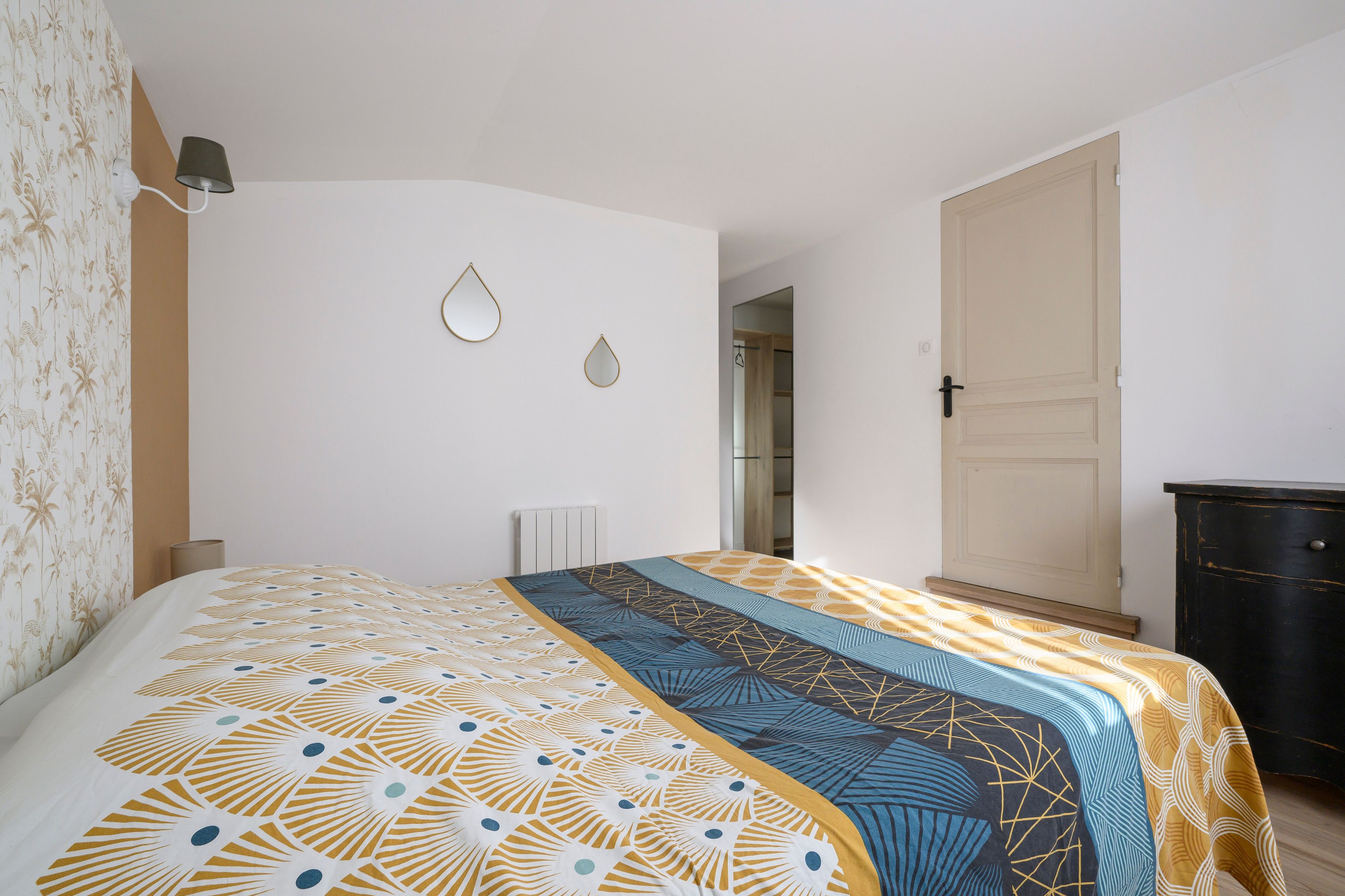 A bedroom with a bed, a radiator, a wardrobe, and a door.