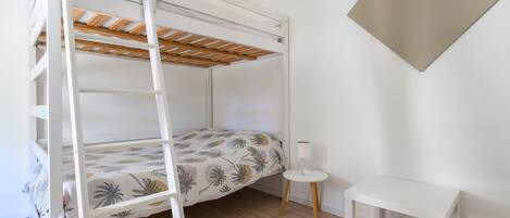 A bunk bed with a ladder, a small bedside table, and a wall-mounted lamp.