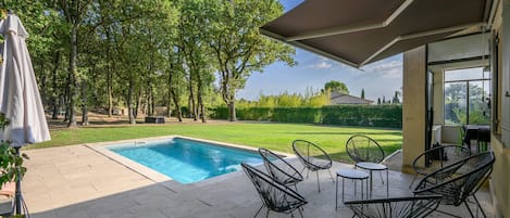 Piscina con zona de patio rodeada de árboles y vista a un área residencial.