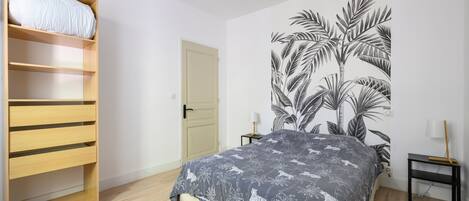 A bedroom with a bed, a wardrobe, a door, and a wall with a leaf pattern.