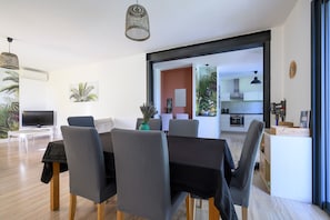 A modern living room with a dining area, a kitchen in the background, and a large window. - Villa La Velleronnaise: private pool, Wi-Fi, air conditioning, near L’Isle sur la Sorgue (Velleron)