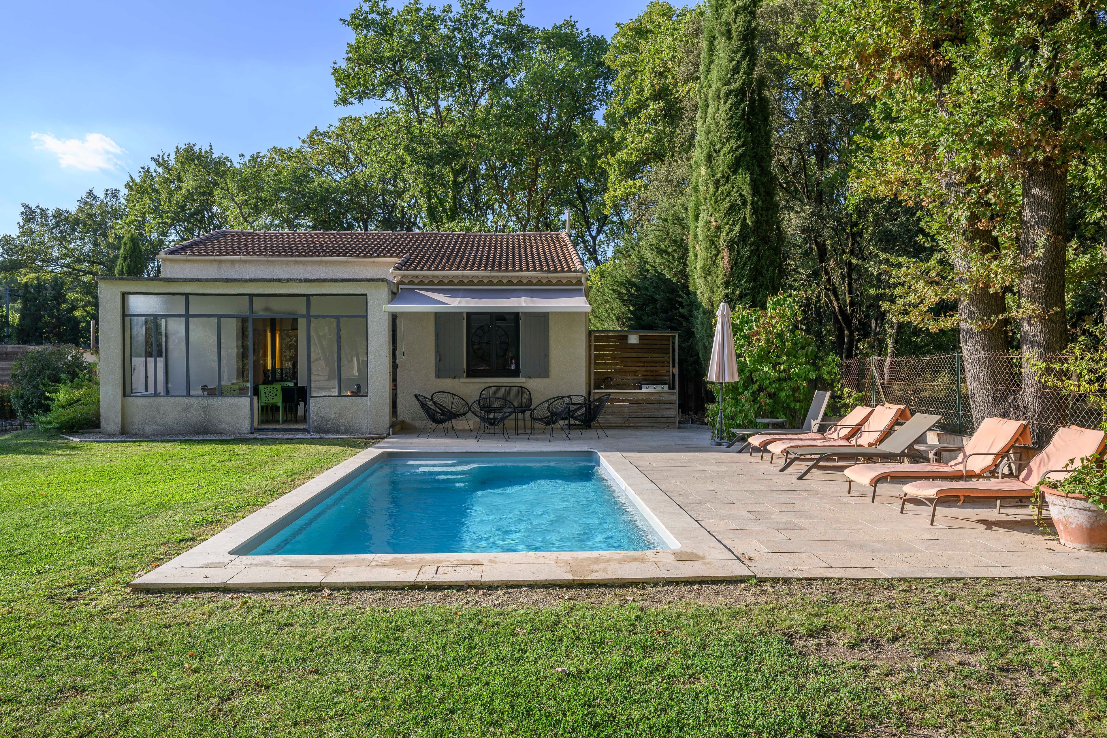 Uma casa moderna com piscina, área de estar externa e jardim.