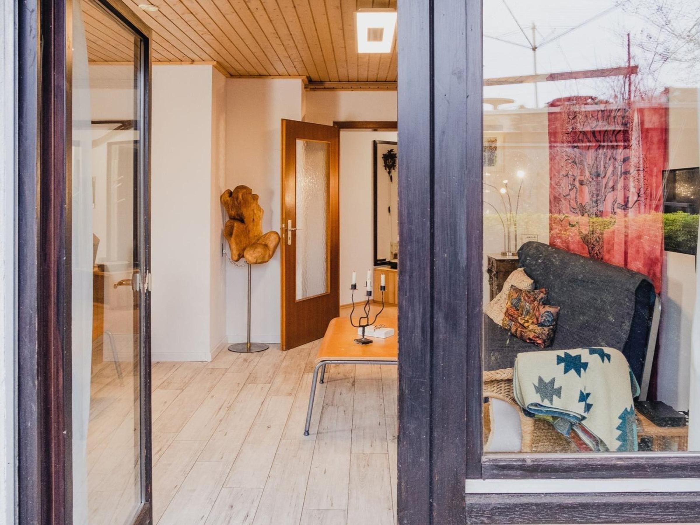 Une pièce dotée d’un plancher en bois, d’un canapé recouvert d’un plaid à motifs, d’une table d’appoint avec des bougies et d’une sculpture décorative en bois.