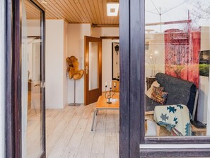 Una habitación con suelo de madera, un sofá con una manta estampada, una mesita auxiliar con velas y una escultura de madera decorativa.