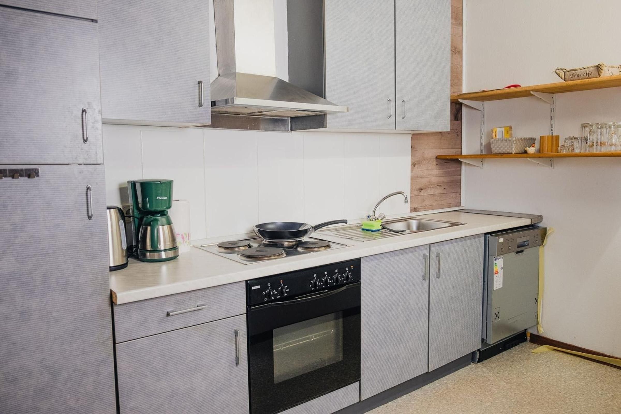A compact kitchen with a stove, oven, sink, and a coffee maker.
