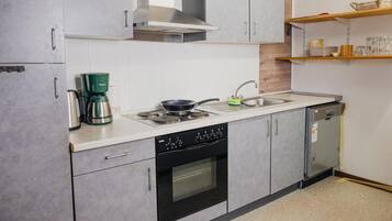 A compact kitchen with a stove, oven, sink, and a coffee maker.