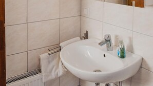 Ein Badezimmer mit einem weißen Waschbecken, einem Spiegel und einem Handtuchhalter.
