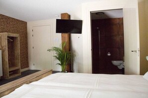 Een hotelkamer met een bed, een aan de muur bevestigde televisie, een houten kledingkast en een badkamer met toilet en douche.