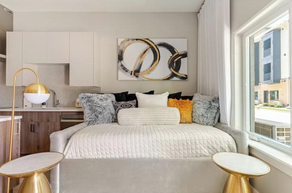 Un dormitorio moderno con cama, mesitas de noche, un cuadro y una ventana.