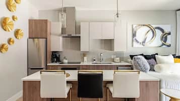 A modern kitchen with a central island, bar stools, and a dining area.