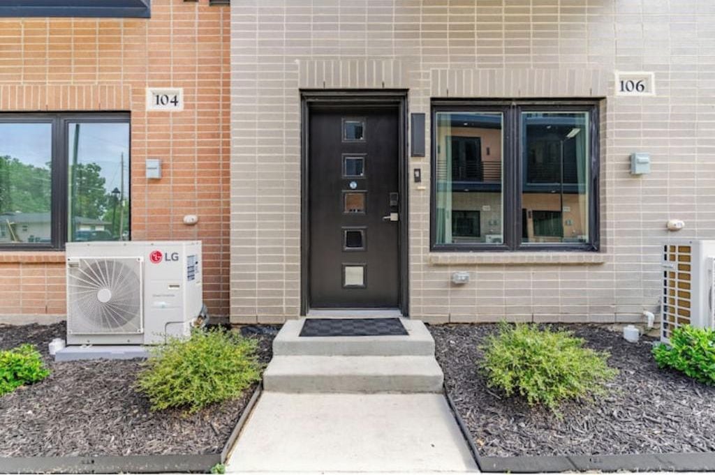 A building with numbered doors, an air conditioning unit, and a small garden area.
