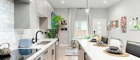 A modern kitchen with white cabinetry, a central island, and a dining area with chairs.