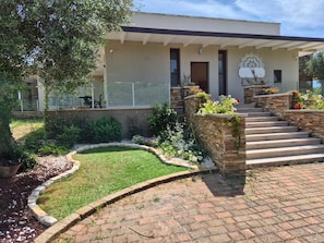 A modern house with a brick pathway leading to a front door, surrounded by a well-maintained garden and a clear sky. - Racconti di Puglia B&B (Polignano a Mare)
