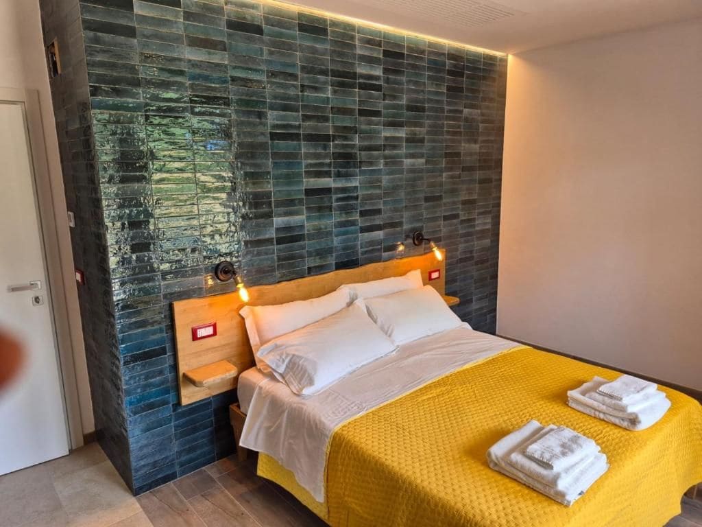 A hotel room with a bed, a nightstand, and a wall with a textured pattern.