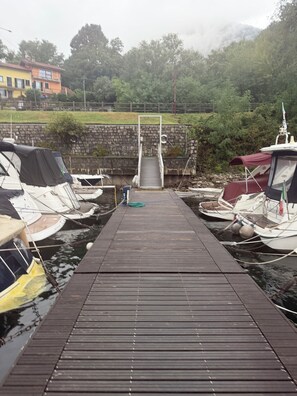 A wooden dock leading to a stone wall with boats docked on either side.