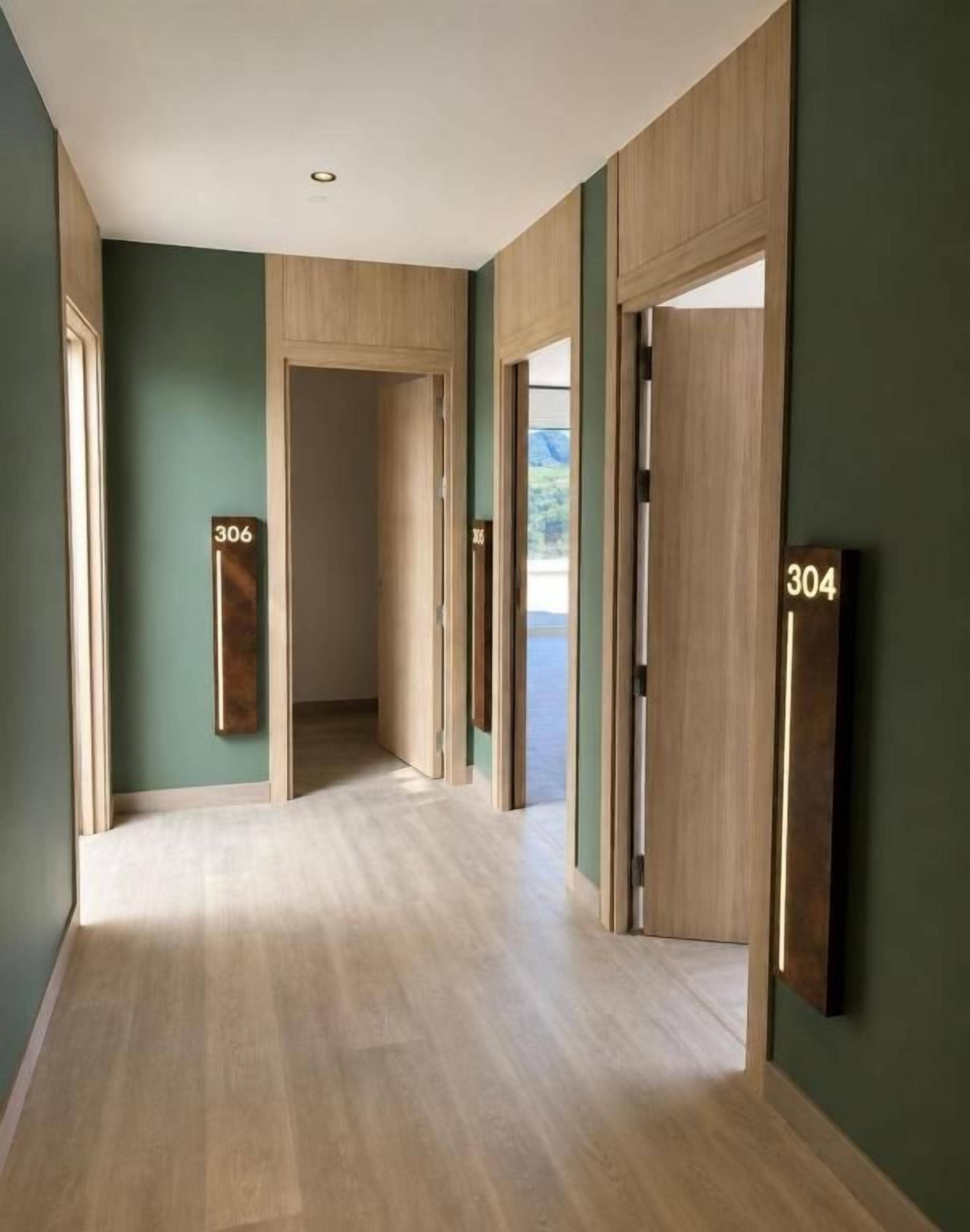 A hallway with wooden flooring, green walls, and doors marked with numbers 304 and 306.
