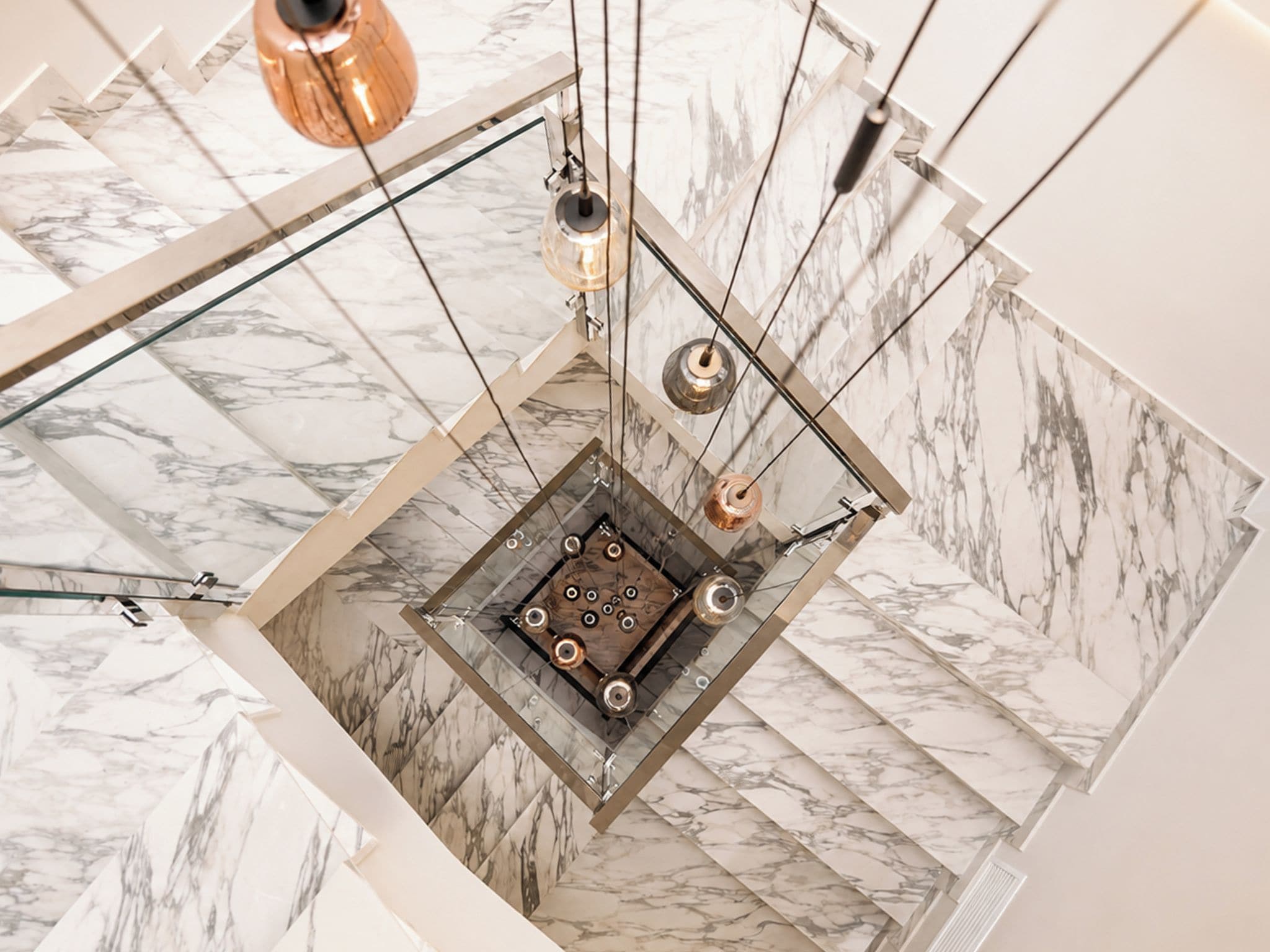 A modern interior with a central square platform, metallic fixtures, and marble-patterned walls.