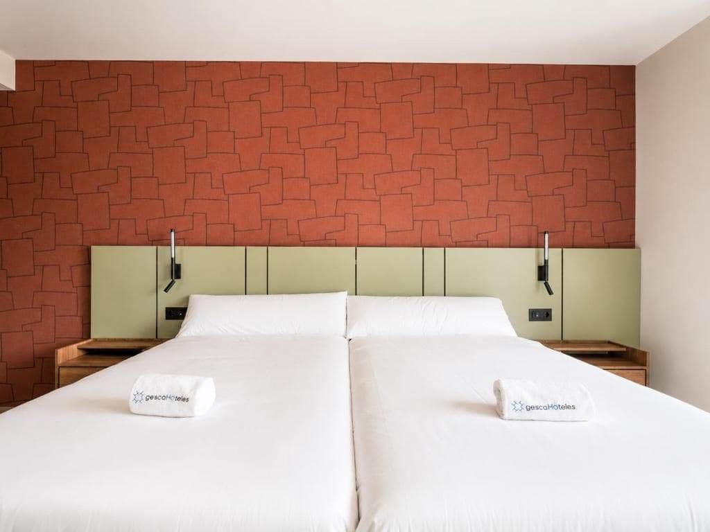 A double bed with white linens, two bedside tables, and a brick-patterned headboard.