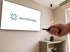 Una mano sosteniendo un bolígrafo señalando una pantalla mural que muestra el logotipo de gescaHotels.