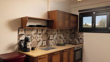 A compact kitchen with wooden cabinets, a built-in oven, and a coffee machine.