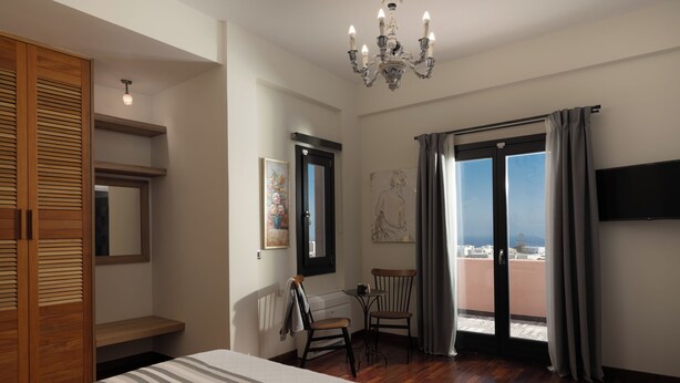 Une chambre d’hôtel comprenant un lit, une armoire en bois, un bureau, une chaise, un balcon avec vue et un lustre.