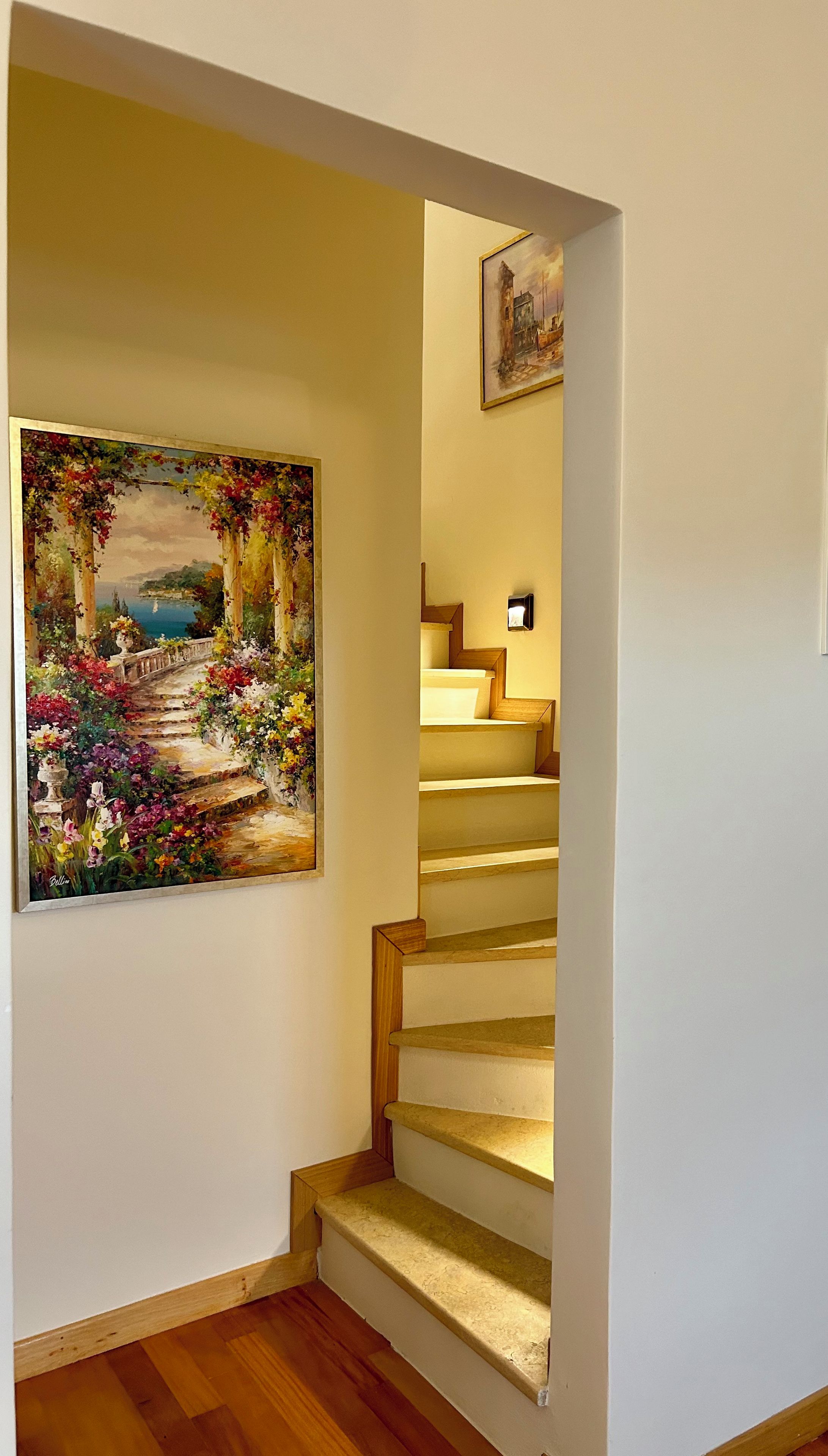 Uma escadaria com um quadro de uma cena de jardim na parede.